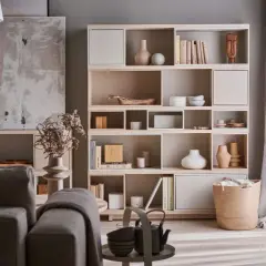Stylowa aranżacja witryny w salonie z książkami, wazonami i dekoracjami.