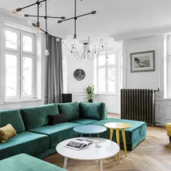Nowoczesny salon z dużą, zieloną kanapą i żółtym fotelem. Kolory ścian zielony z szarym, białe okna i sztukateria.
