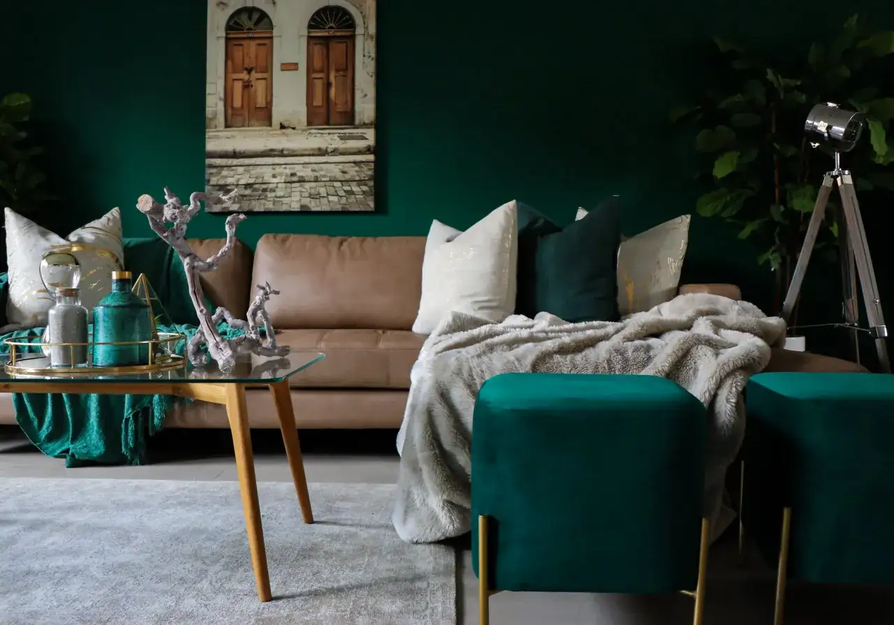 Elegancki salon z kanapą w kolorze cappuccino, zielonymi akcentami i złotymi dodatkami. Idealnie, gdy kolor cappuccino z czym łączyć, by stworzyć przytulną atmosferę.